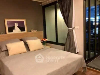 Cozy bedroom with modern decor and large window offering stunning city view.