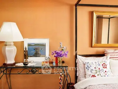 Charming bedroom with elegant decor and cozy bedding, featuring a stylish lamp and decorative accents.