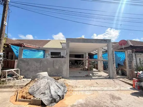 Under-construction house with exposed framework and blue tarps, showcasing potential for customization.