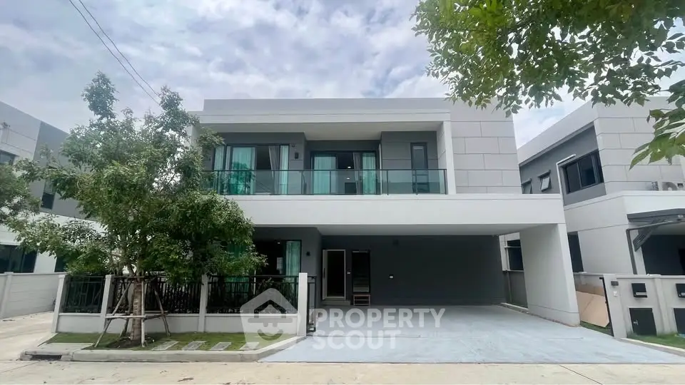 Modern two-story house with large balcony and driveway in a serene neighborhood.