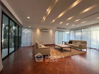 Spacious living room with elegant parquet flooring and large windows offering natural light.