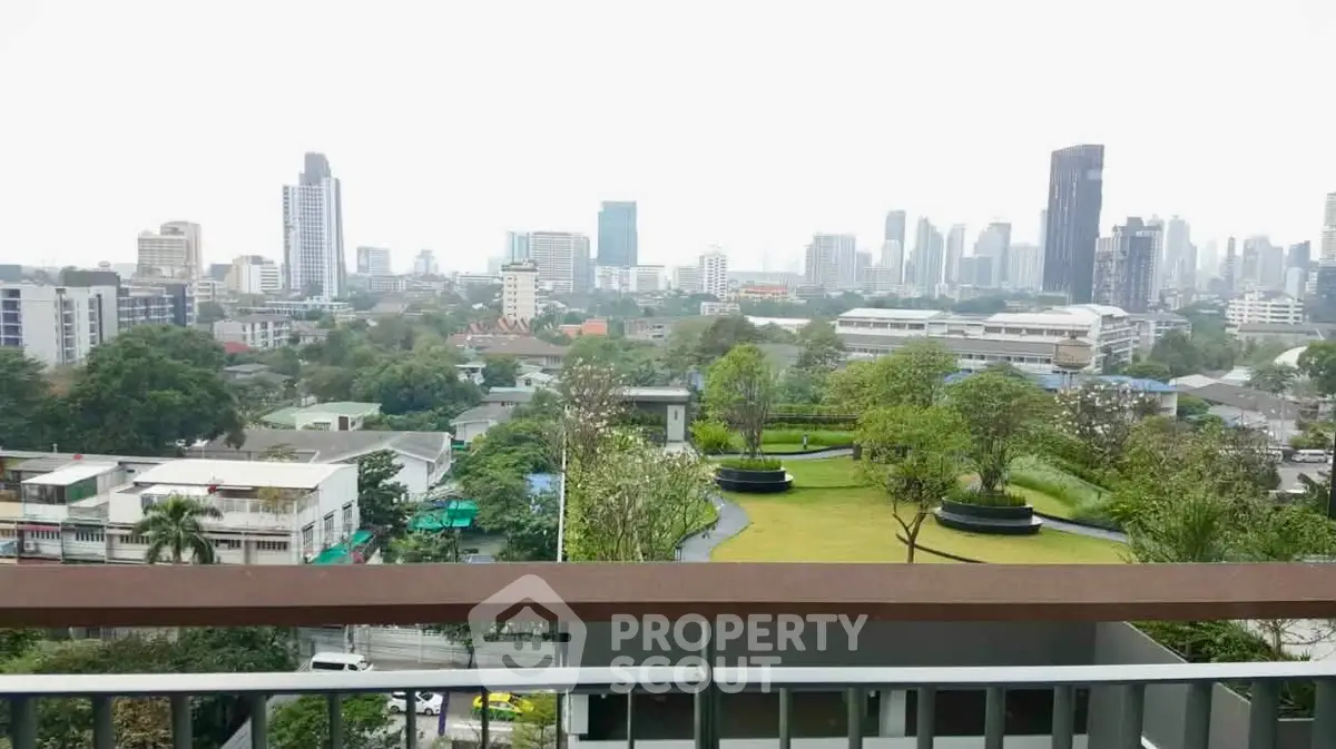 Stunning cityscape view from a high-rise balcony overlooking lush greenery and urban skyline.