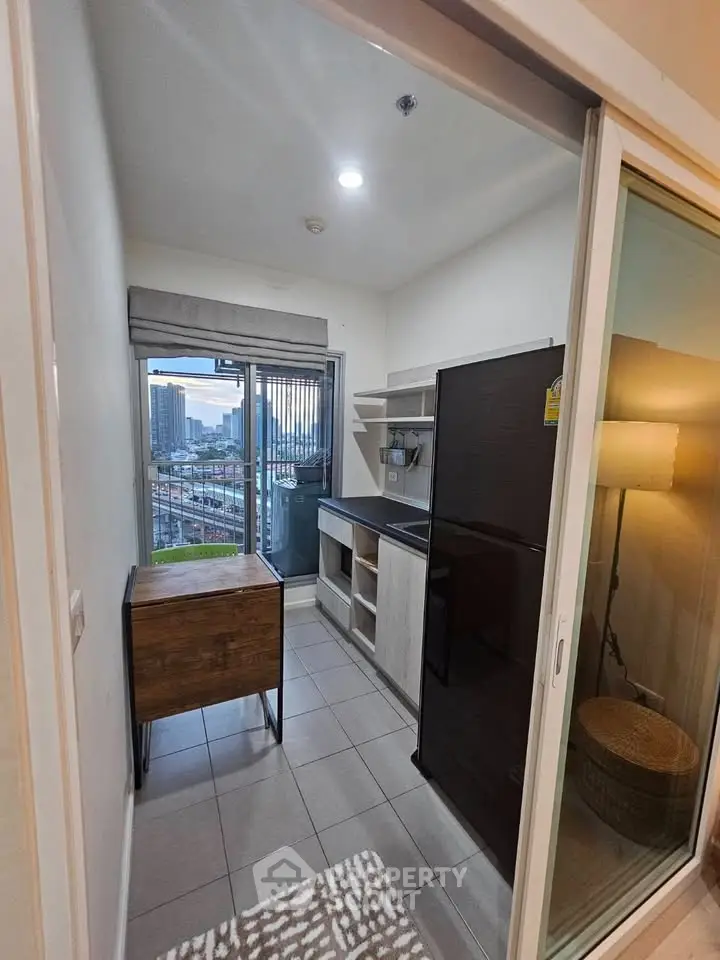 Compact kitchen with city view, featuring modern appliances and sleek design in urban apartment.