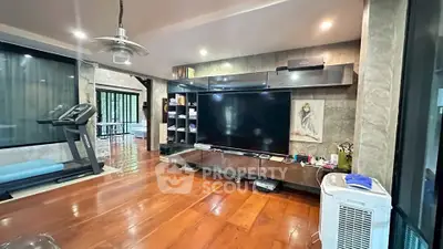 Spacious living room with modern entertainment setup and exercise equipment.