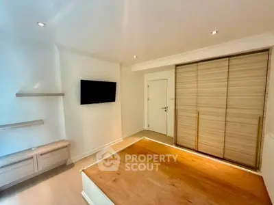 Modern bedroom with built-in wardrobe and wall-mounted TV in a minimalist design.
