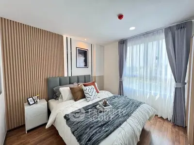 Modern bedroom with stylish decor and large window offering natural light.