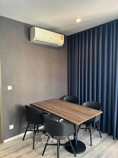 Modern dining area with sleek table and chairs, featuring air conditioning and elegant curtains.