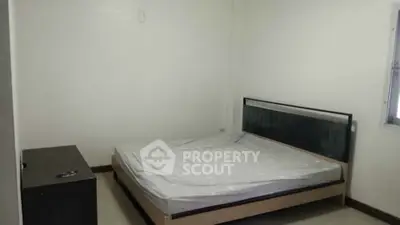 Minimalist bedroom with bed and dresser in a simple, clean design.