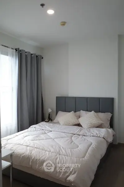 Cozy bedroom with modern decor and ample natural light, perfect for relaxation.