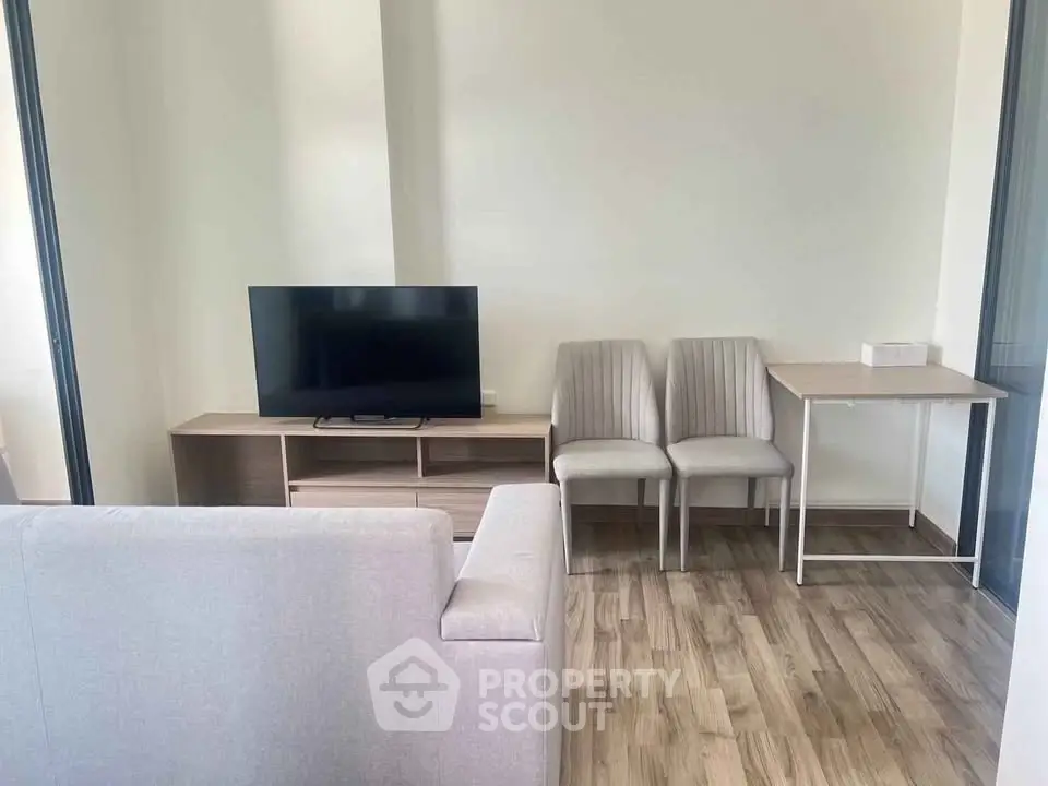 Modern living room with sleek TV setup and cozy seating area on wooden flooring.