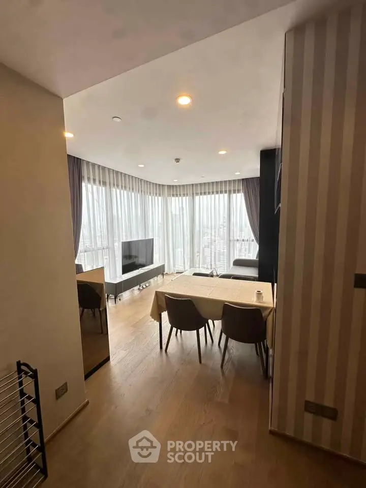 Modern living room with dining area and panoramic city view, featuring elegant decor and natural light.