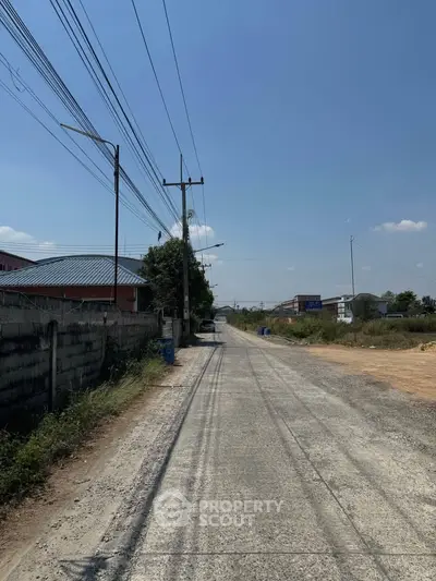 Expansive view of a quiet suburban road with clear skies and surrounding greenery.