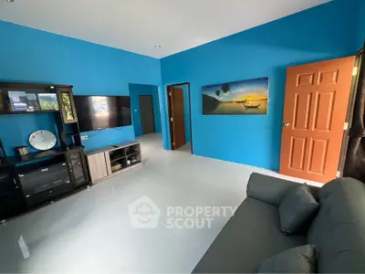 Vibrant living room with blue walls, modern furniture, and a wall-mounted TV, perfect for relaxation.