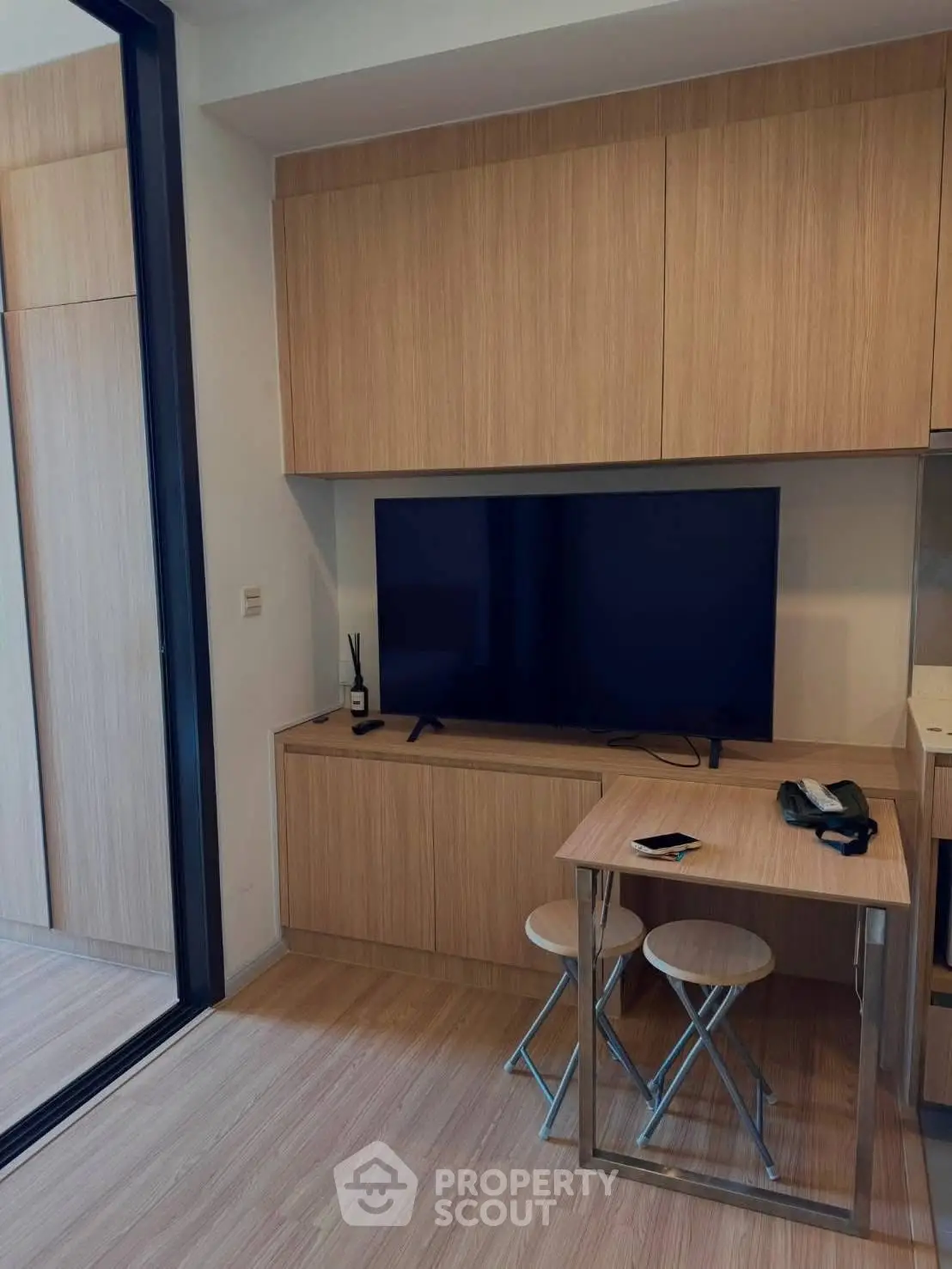 Modern living room with sleek wooden cabinetry and flat-screen TV, ideal for contemporary urban living.