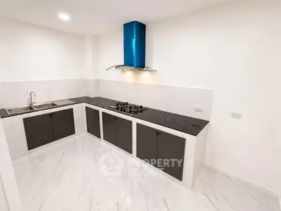 Modern kitchen with sleek black countertops and gas stove in a minimalist design.