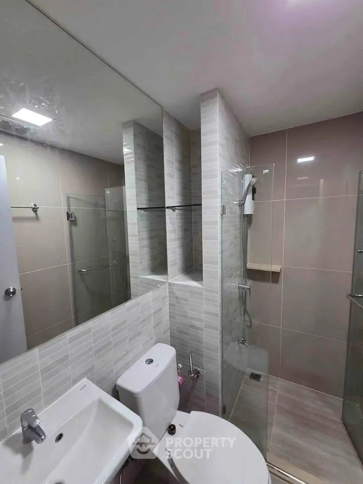 Modern bathroom with sleek design, featuring glass shower and stylish tiles.