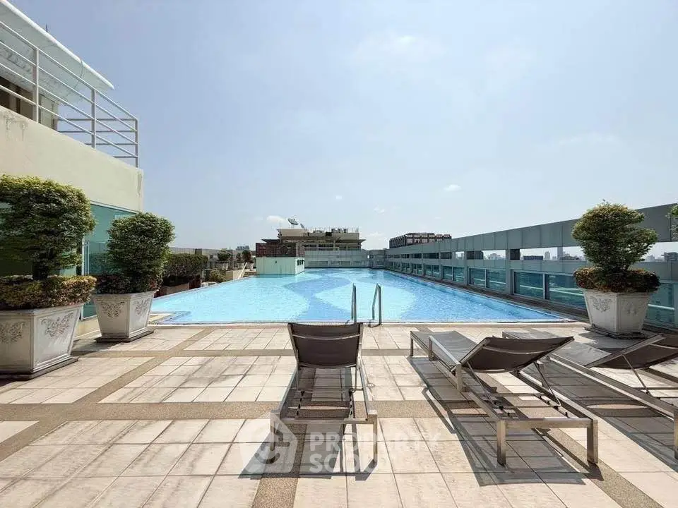 Luxurious rooftop pool with sun loungers and city skyline view, perfect for relaxation and leisure.