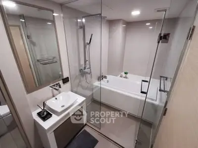 Modern bathroom with glass shower and bathtub in sleek apartment