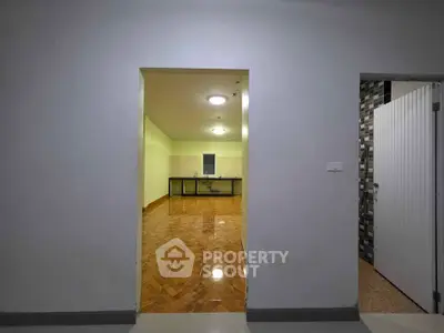 Spacious open-plan living area with glossy wooden flooring and modern kitchen setup.