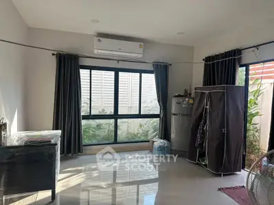 Spacious living room with large window, air conditioning, and modern appliances.
