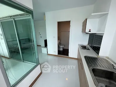 Modern apartment with sleek kitchen and glass-walled bedroom, offering a contemporary urban living experience.