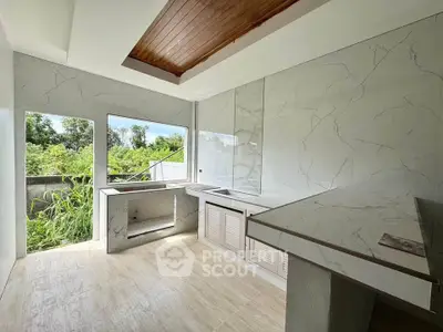 Modern kitchen with marble countertops and large windows overlooking greenery