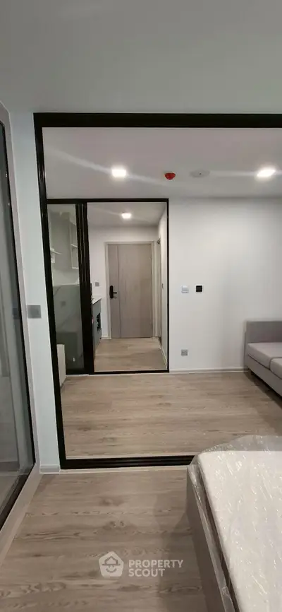 Modern apartment interior with wooden flooring and large mirror