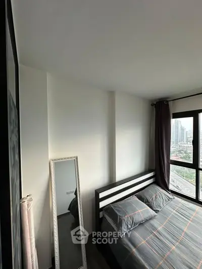 Modern bedroom with city view, featuring stylish decor and large windows.
