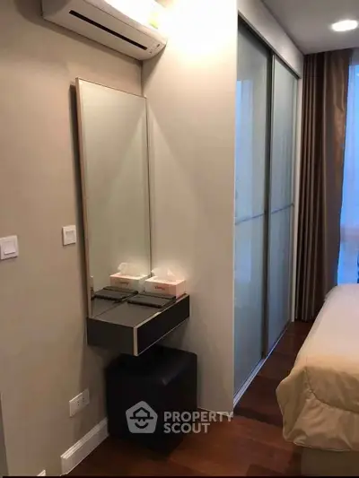 Modern bedroom with sleek design, featuring a wall-mounted mirror and air conditioning unit.