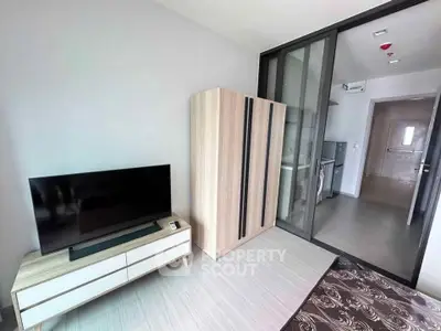 Modern living room with sleek TV stand and wardrobe, featuring sliding glass doors to kitchen area.