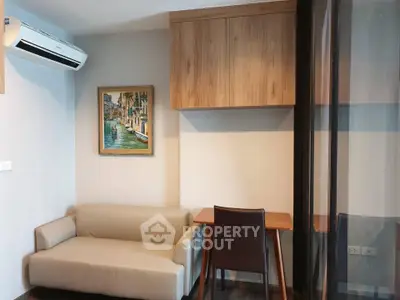 Modern living room with compact sofa, wall art, and wooden cabinetry