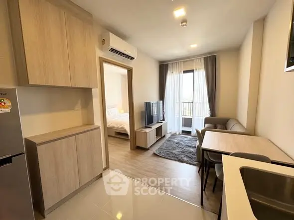 Modern open-plan living room with kitchen and balcony access in stylish apartment.