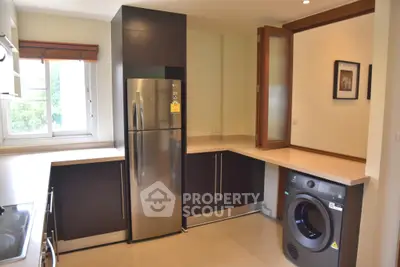 Modern kitchen with stainless steel fridge and washing machine, featuring sleek cabinetry and ample counter space.