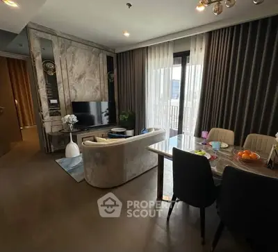 Elegant living room with modern decor and dining area, featuring large windows and stylish furnishings.