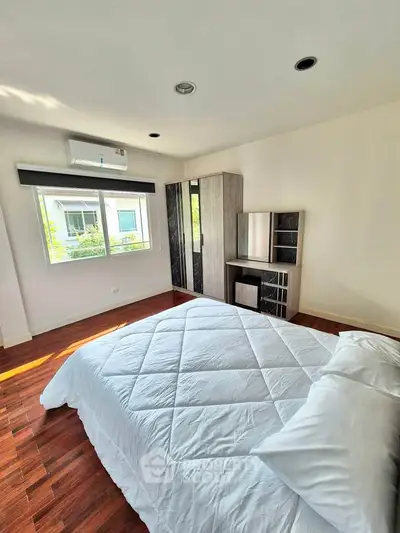 Spacious bedroom with modern furniture and large window offering natural light.