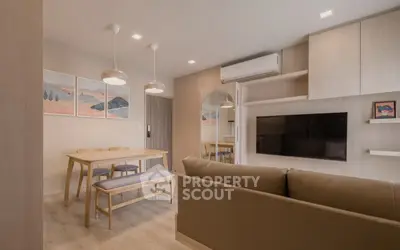 Modern living room with stylish decor, wall-mounted TV, and dining area in open layout apartment.