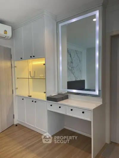 Modern bedroom with built-in storage and illuminated mirror, showcasing sleek design and functionality.