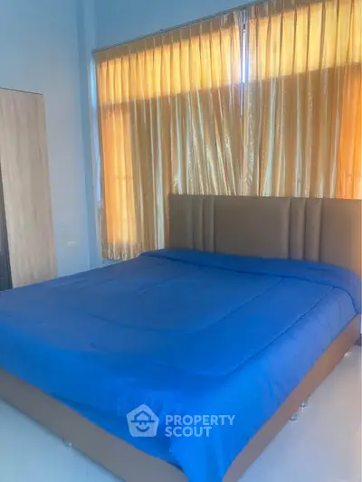 Spacious bedroom with large bed and elegant curtains, perfect for relaxation.