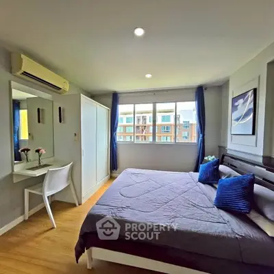 Spacious bedroom with modern decor and large window offering city views.