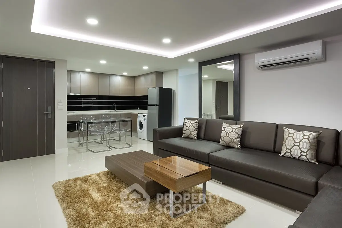 Modern living room with sleek kitchen, stylish furniture, and ambient lighting in a contemporary apartment.