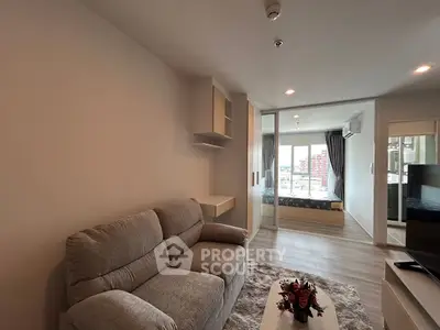 Modern living room with cozy sofa and view into bedroom, bright and inviting space.