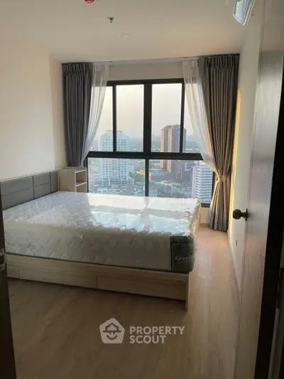 Modern bedroom with large window offering stunning city view, featuring a comfortable bed and elegant curtains.