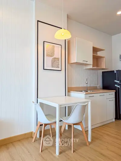 Modern kitchen with sleek white cabinets, compact dining area, and stylish decor in a cozy apartment.
