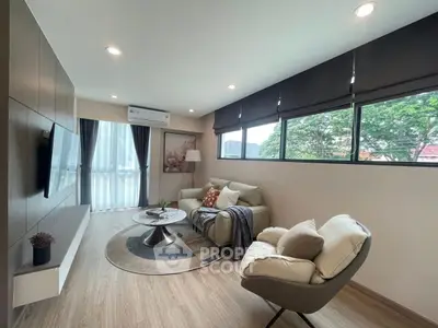 Modern living room with stylish furniture and large windows offering natural light and greenery views.