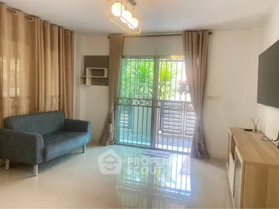 Bright living room with modern decor and large window overlooking greenery.