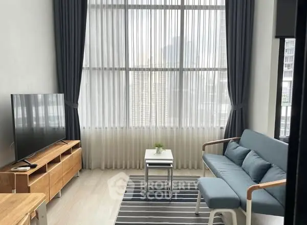Modern living room with high ceilings, large windows, and stylish furniture in a city apartment.