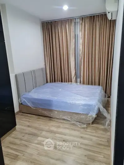 Cozy bedroom with wooden flooring and elegant curtains in modern apartment.