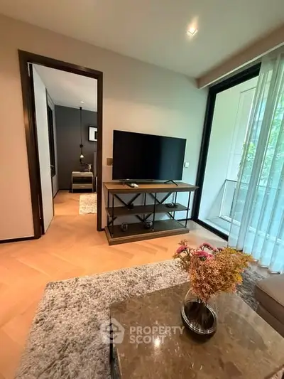 Modern living room with TV, cozy decor, and balcony view in a stylish apartment.