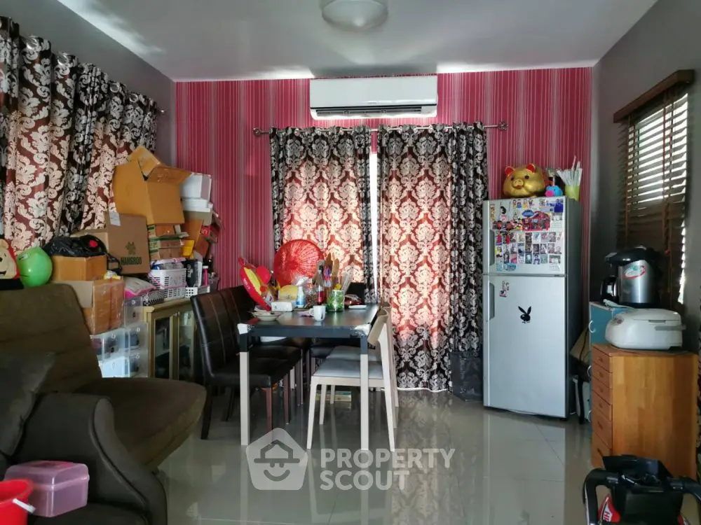 Cozy living room with vibrant decor and compact dining area, featuring a small fridge and air conditioning.