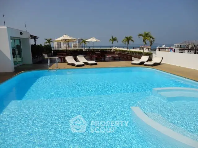 Luxurious rooftop pool with ocean view and sun loungers, perfect for relaxation.